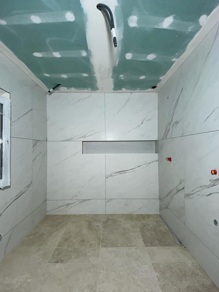 Salle de bains pendant le chantier : plafond en plaques hydrofuges avec bandes en cours, doublages carrelés et niche